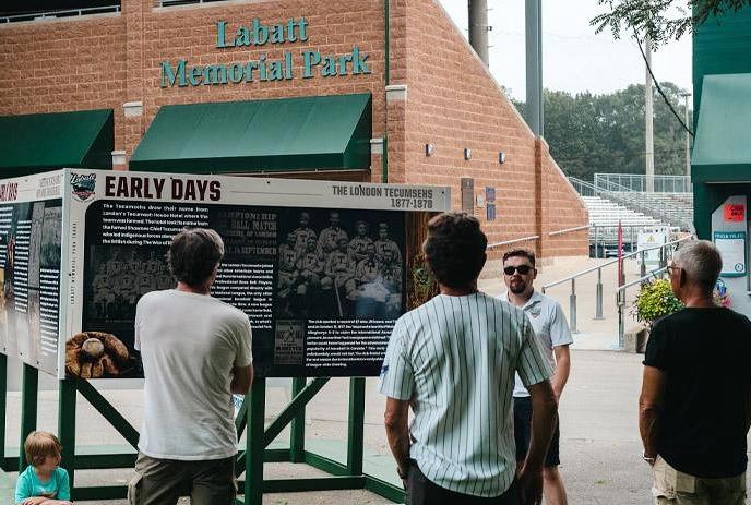 A group of people listening to a guide speaking at Labatt Memorial Park during a tour of the grounds located in London, Ontario