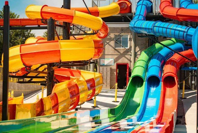 Bright twisting waterslides in many colors looping around a tall structure above a splash area.