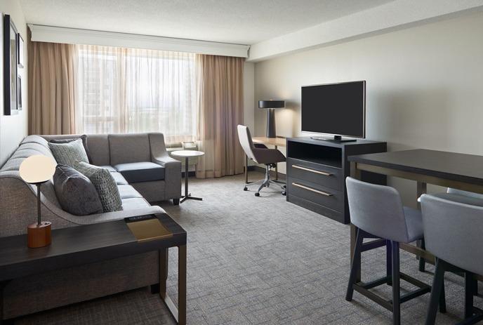 hotel suite includes indoor furniture like a chest of drawers, a table, a bed, and a chair.