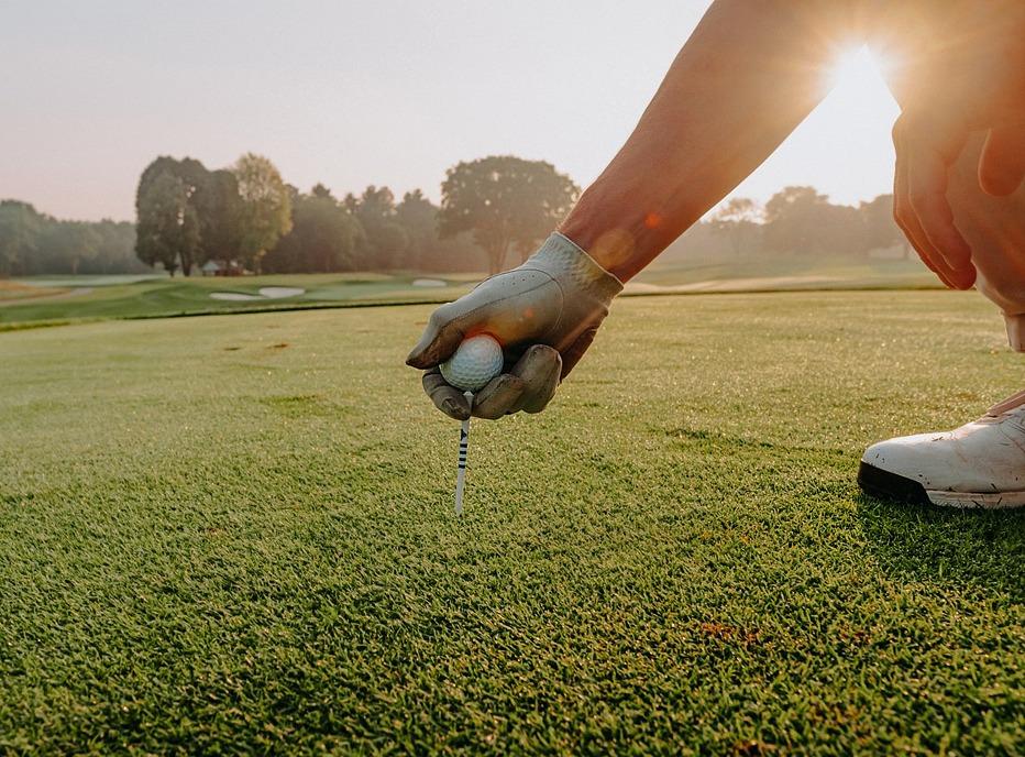 A person placing a golf ball on a tee, on a golf course located in London, Ontario