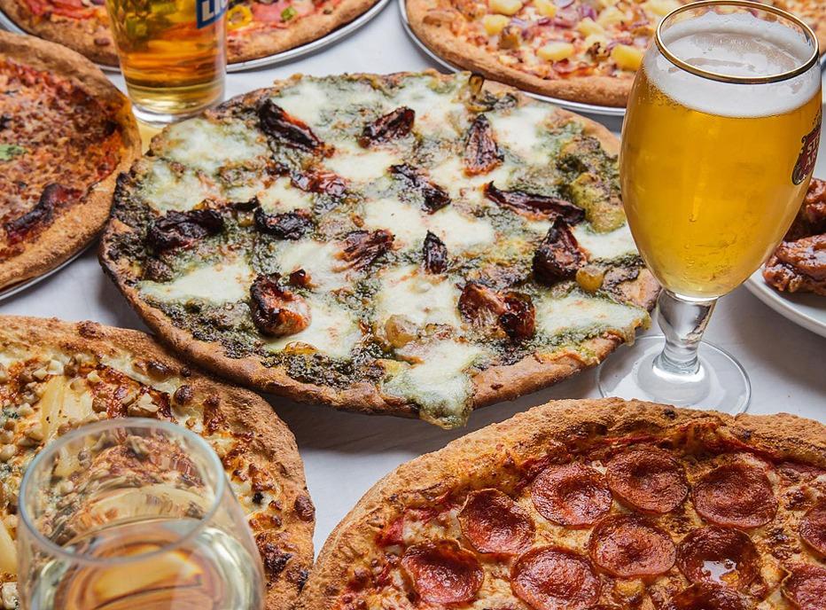 A table top view with several pizzas and a glass of beer from Pizza Projekt, located in London, Ontario