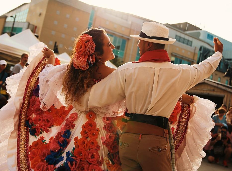 A couple is dancing in traditional Columbian clothing outdoors at the Colombian Gastronomy Festival in London, Ontario