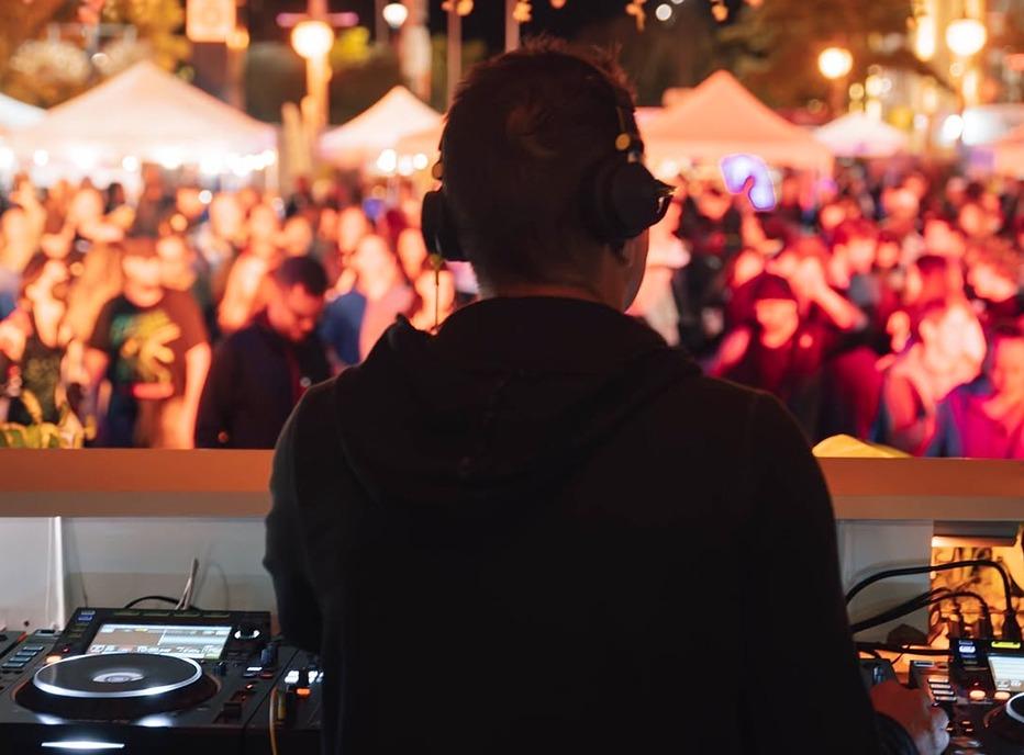 A Dj looking out into a crowd gathered outdoors at the Covent Garden Market in London, Ontario for the Elevate Festival