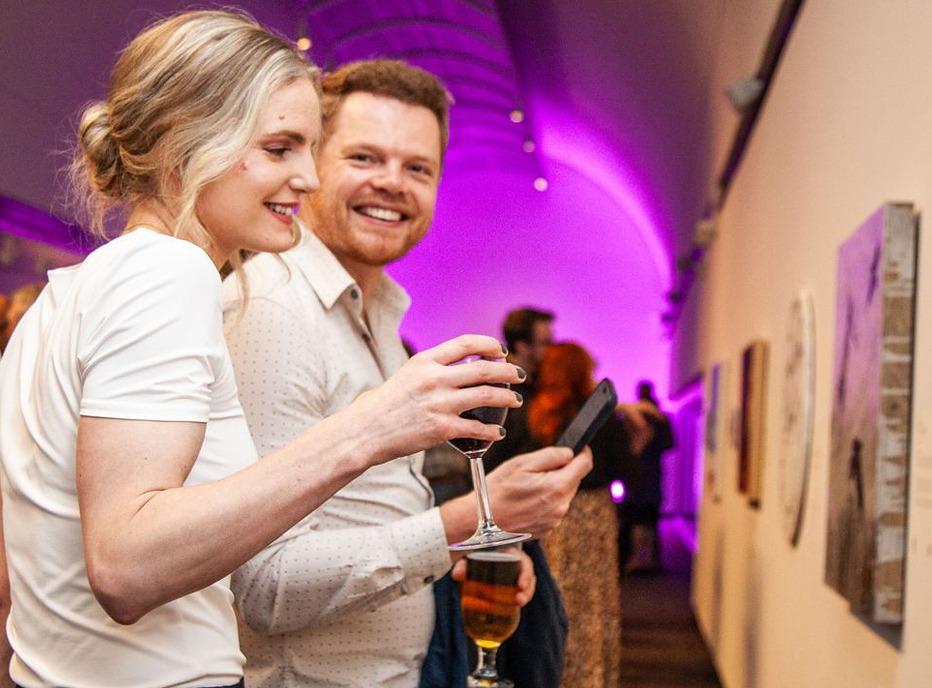 A male and female observing art with a crowd of people in the background at Museum London. located in London, Ontario