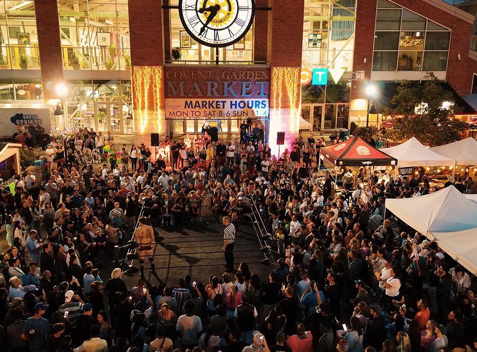 A large gathered outdoors at night in front of Covent Garden Market, located in London, Ontario