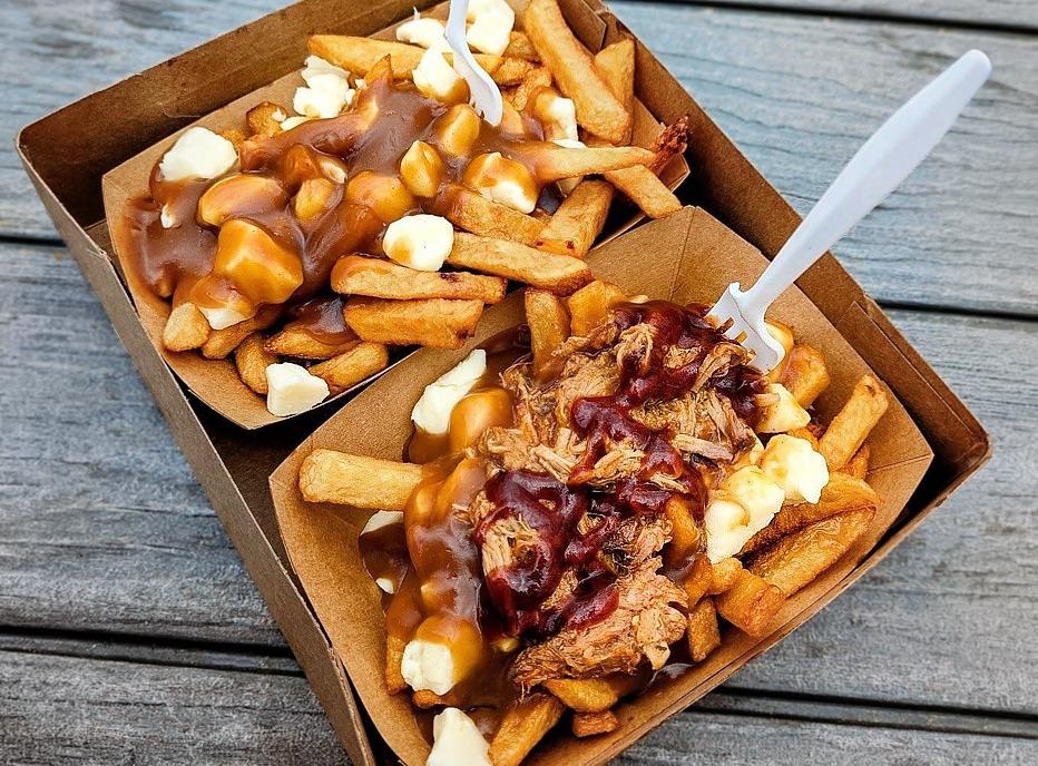 A table top view of a serving of poutine on a wooden table