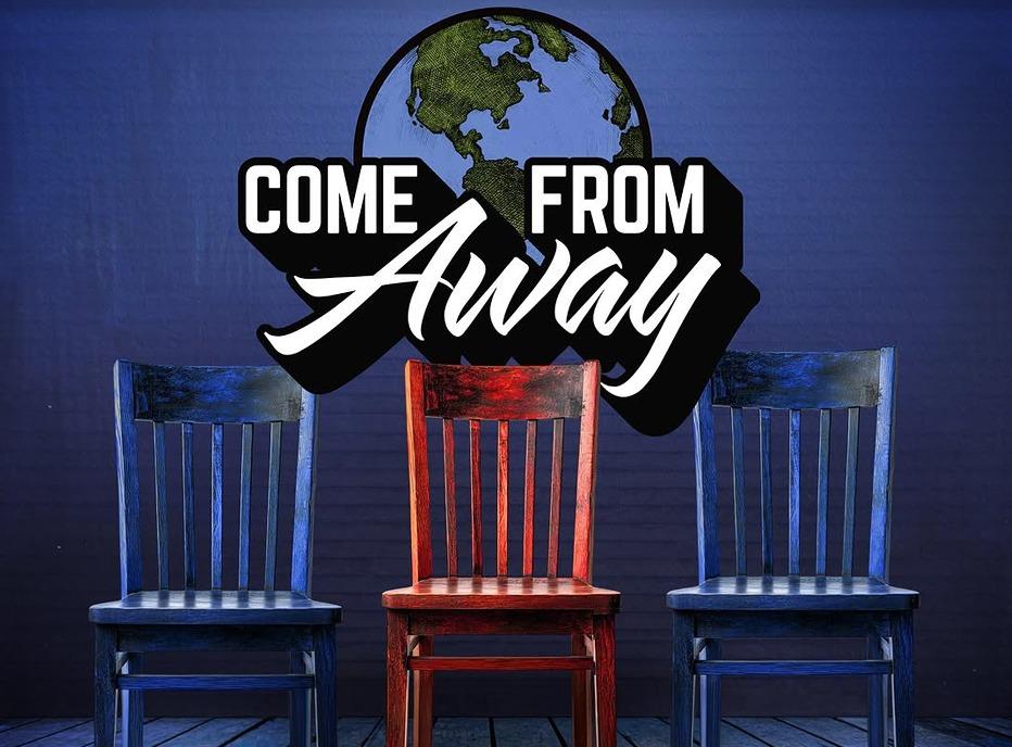 Three wooden coloured chairs, two are blue, one is red with the logo of the production 'Come From Away' in the background