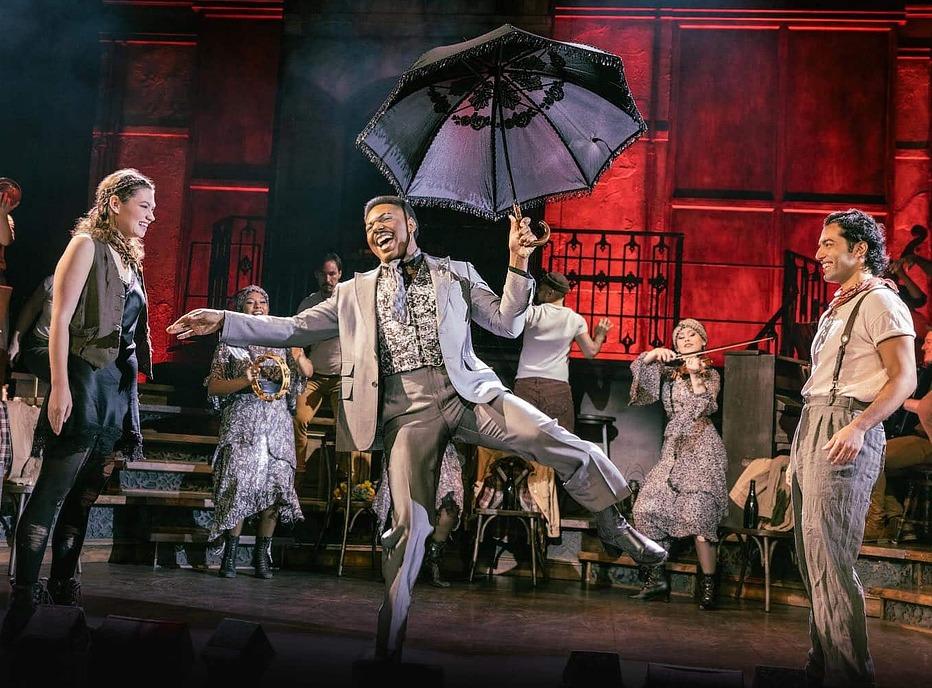 Various actors performing live on stage a scene from the Broadway Musical Hadestown