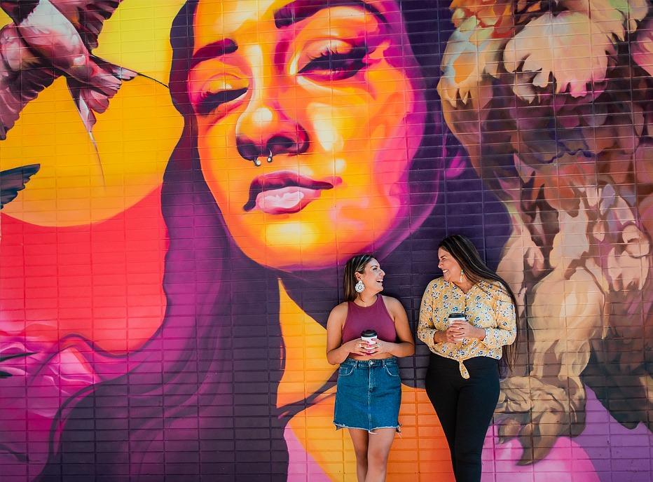 Two females standing in front of a colourful mural located in downtown London, Ontario