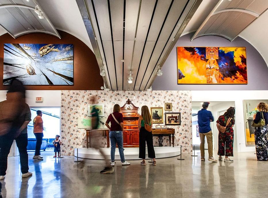 Various people observing artworks on display at an exhibition held at Museum London, located in London, Ontario