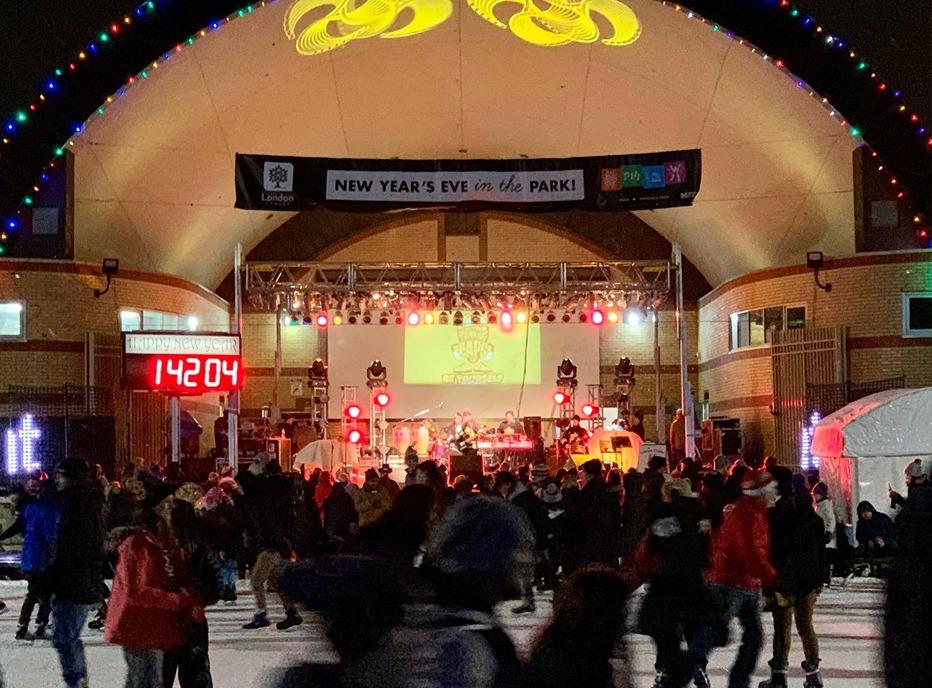 A large group of people skating outdoors at Victoria Park while a band plays live music on stage on New Years Eve in London, ON