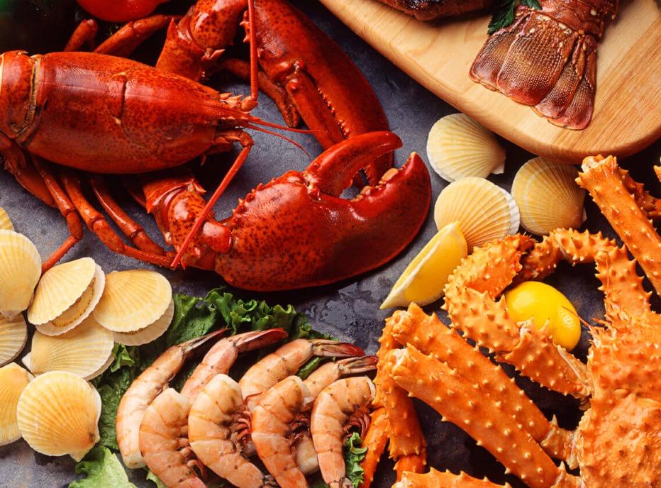 A table top view of prepared seafood including lobster, clams, shrimp and crab.
