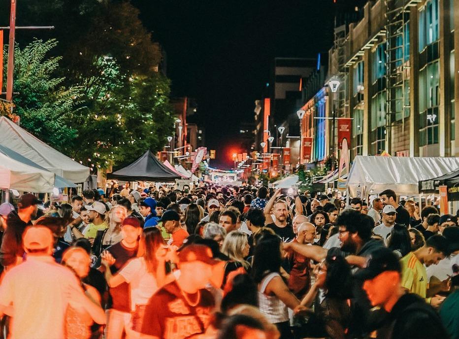 A large group of people gathered outdoors on Dundas Street in downtown London, Ontario during a festival at night
