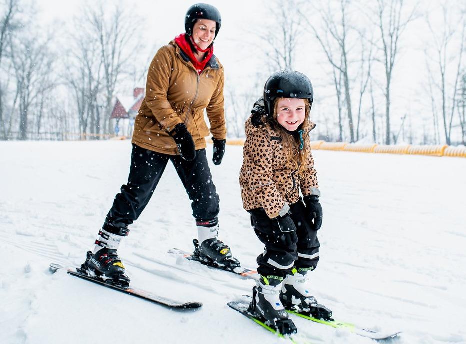 A mother and her young daughter skiing down a hill at Boler Mountain located in London, Ontario