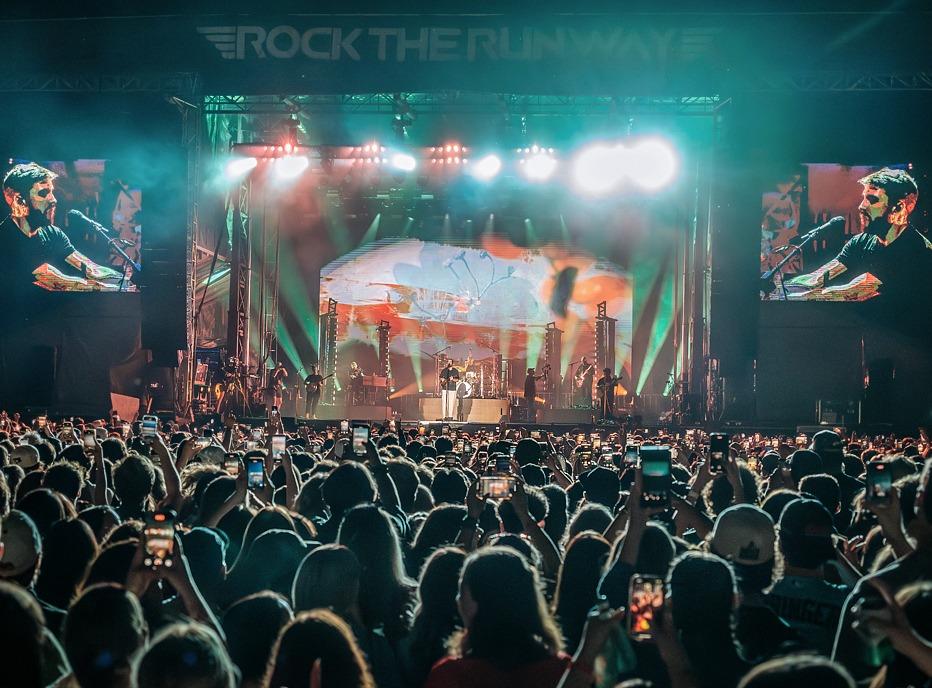 A large crowd gathered outdoors watching musicians play live on a stage at night at Rock the Runway located in London, ON