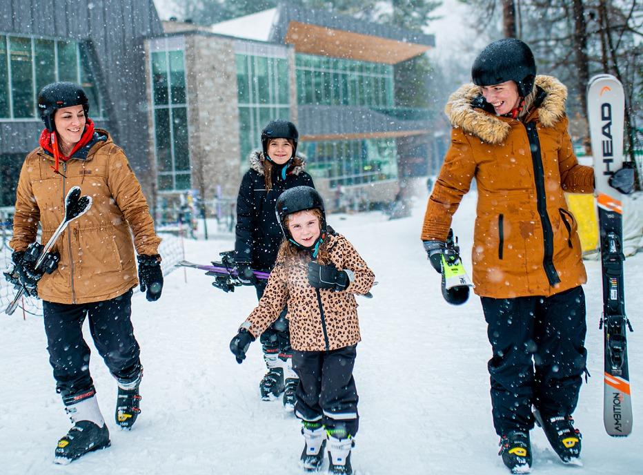 A family holding skis and walking at Boler Mountain, located in London, Ontario