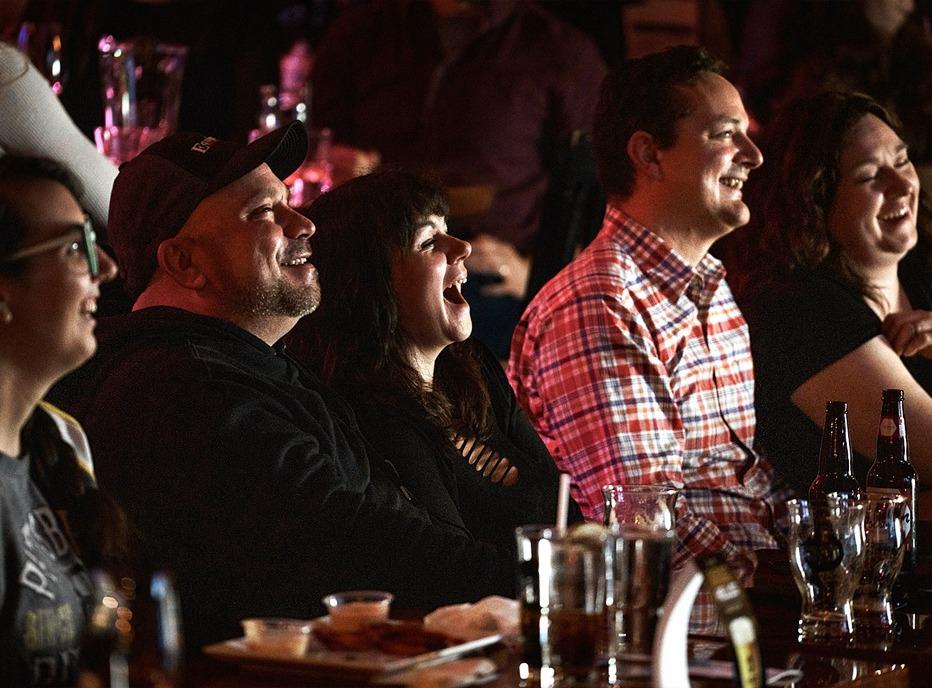 A group of people laughing and watching a comedian live at a club