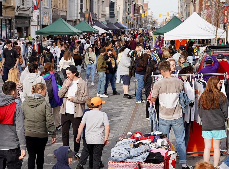 A crowd of people gathered outdoors shopping at a vintage market in downtown London, Ontario