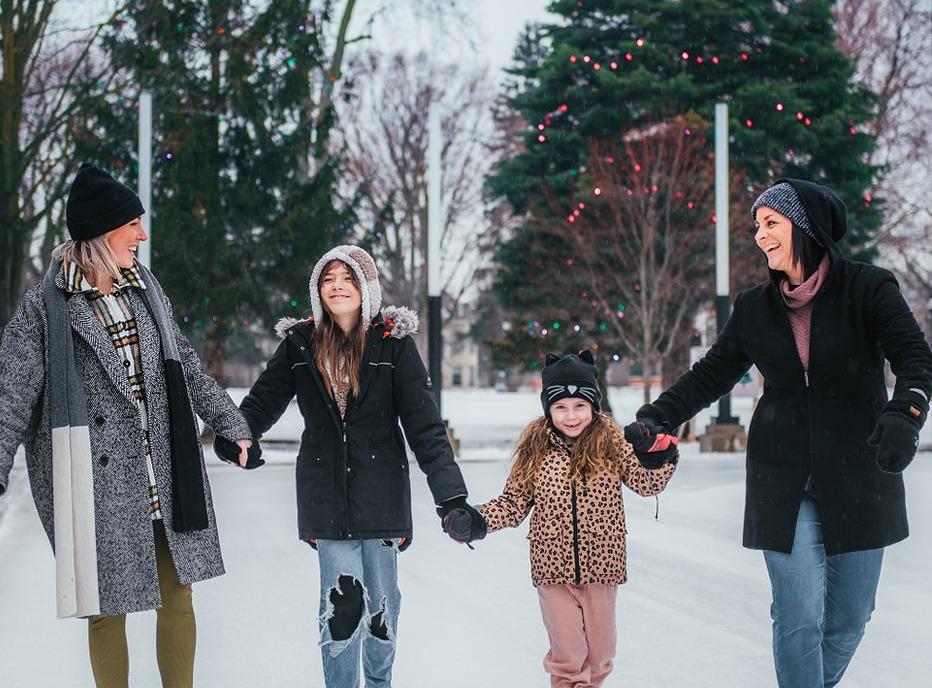 A family holding hands while skating at Victoria Park in the winter, located in London, Ontario