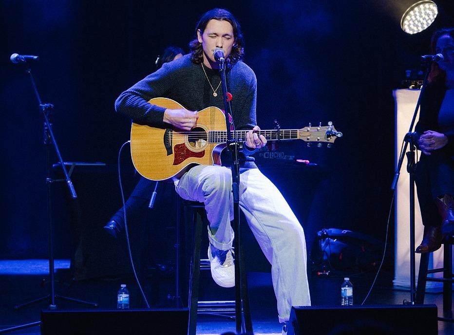 Musician John Fellner playing an acoustic guitar live on stage at the London Music Hall