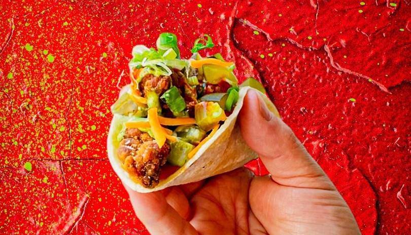 Chicken taco being held against a red background from The Mule restaurant located in London, Ontario