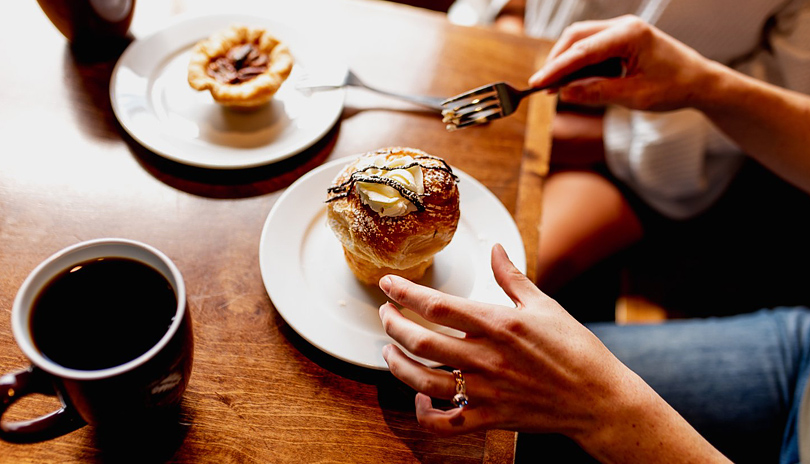 A female holding a fork about to eat a cruffin pastry from Black Walnut Bakery Cafe located in London, Ontario, Canada