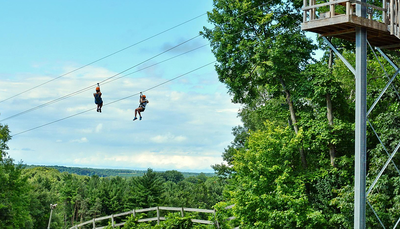 Two people zip lining at Boler Mountain's Treetop Adventure Park located in London, Ontario