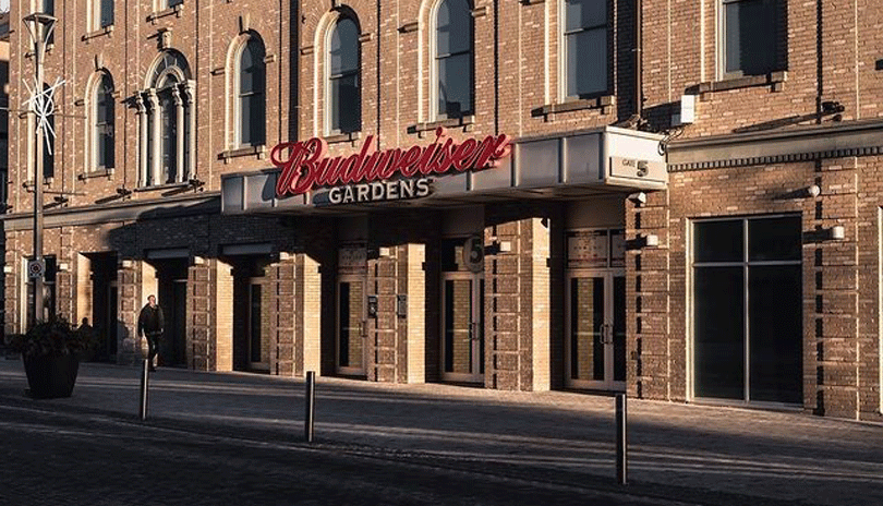 Budweiser Gardens building and sign lit up by a sunset.
