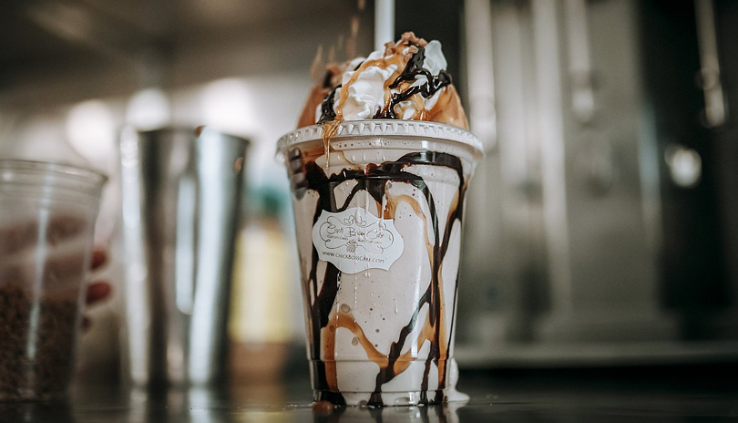 A milk shake drink drizzled with caramel and whip cream sitting on a table from Chick Boss Cake located in London, Ontario