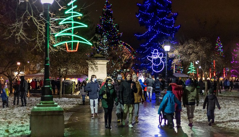 Groups of people walking in decorated Victoria Park with lights and Christmas decorations during the holidays