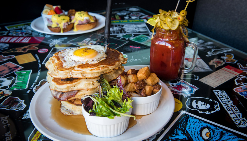 Various plated dishes and drinks displayed on a colourful table at The Early Bird located in London, Ontario