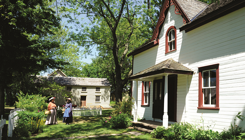 Exterior view of a historic building with people dressed as historic characters in Fanshawe Pioneer Village located in London, Ontario