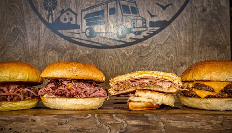 Various sandwiches on display from Field to Truck on a wooden plank