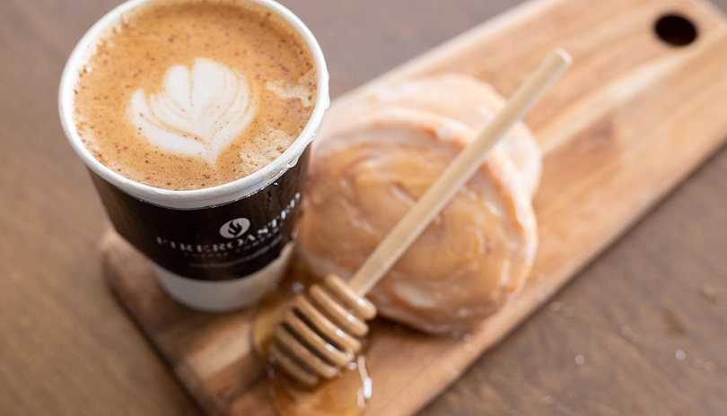 A close up of a cup of coffee sitting on a wooden plank from Fire Roasted Coffee Co. located in London, Ontario