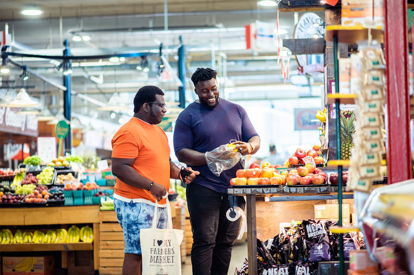 Two people shopping for produce from a vendor at Covent Garden Market located in London, Ontario