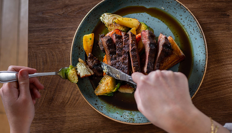 A table top view of a person cutting into a dish prepared by Garlic's of London restaurant located in London, Ontario