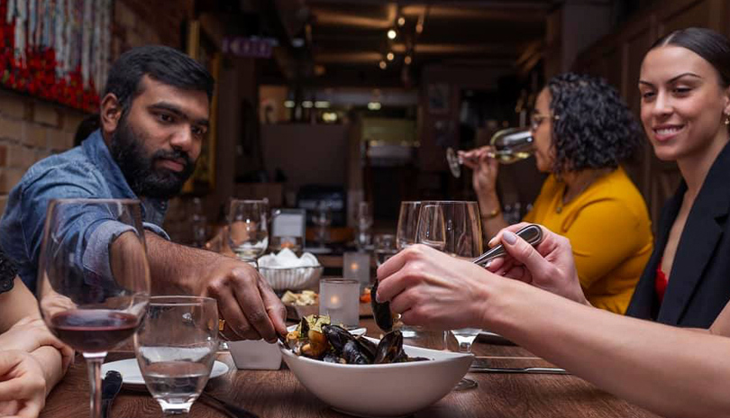 A group of friends dining together and sharing food at Garlic’s Of London located in London, Ontario