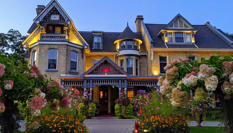 Outdoor entrance of the Idlewyld Inn & Spa with lush colourful flowers, locate din London, Ontario, Canada