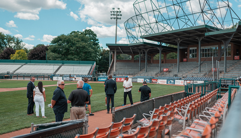 A group of people standing on the baseball field of Labatt Park, The World's Oldest Operating Baseball Grounds located in London, Ontario, Canada