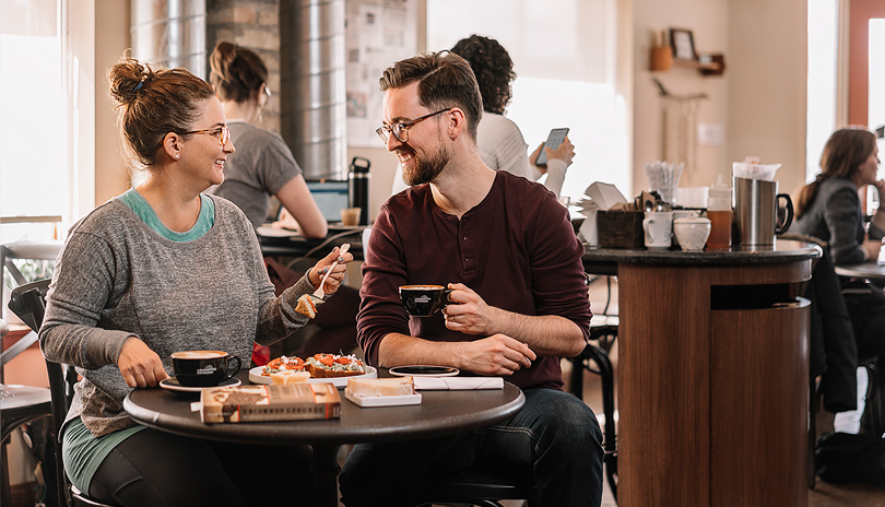 A male and female sitting together and enjoying lunch and coffee at Locomotive Espresso in London, Ontario