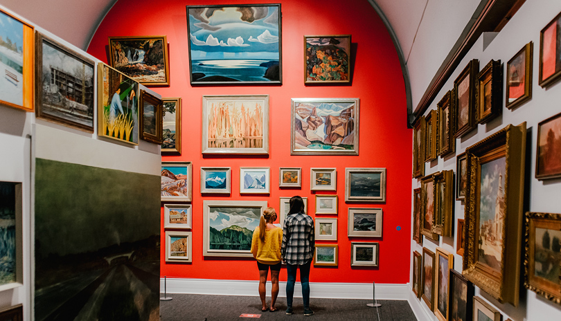 Two females observing several works of art on display at Museum London located in London, Ontario