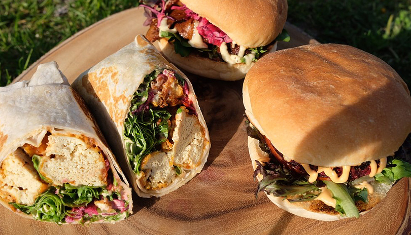 Various sandwiches on display from New Leaf food truck on a wooden plank