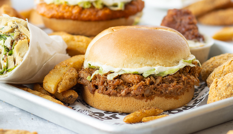 A plant based burger on a tray surrounded by french fries and other sandwiches from Odd Burger