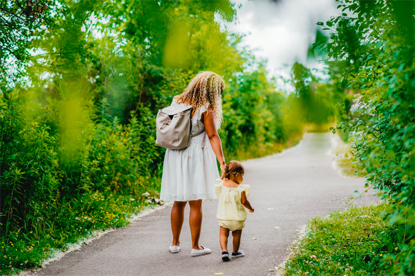 A mother and her young child walk on a paved path through Westminster Ponds located in London, Ontario
