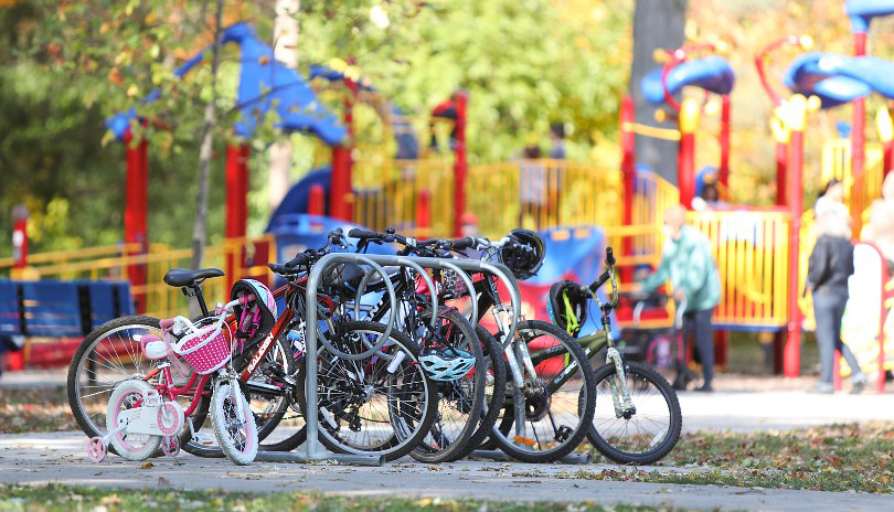 Various bikes parked at a bike rack at a London, Ontario playground
