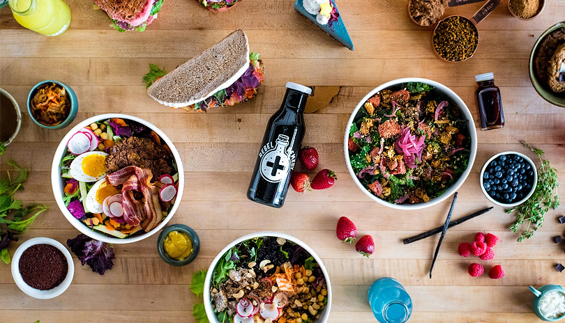 Various food items from Rebel Remedy Health Bar displayed on a table along with cups of fresh juice