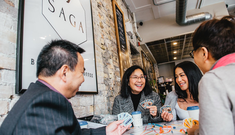 A family enjoying a card game and drinking coffee atSaga Board Games & Coffee located in London, Ontario