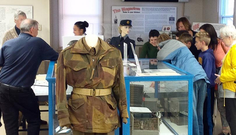 A small group of kids and adults viewing historic objects on display at The Secrets of Radar Museum located in London, Ontario