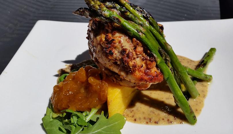Chicken and asparagus on a potato with greens and sauce 