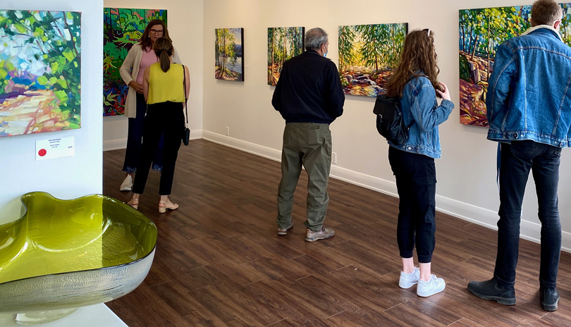 A group of people looking at various paintings on display at Westland Gallery located in London, Ontario